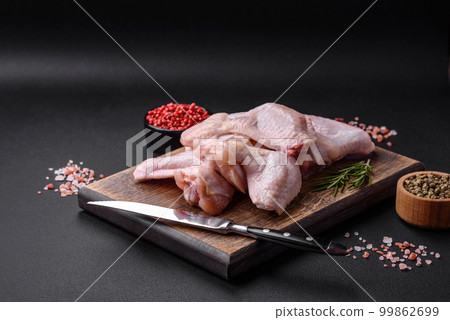 Raw chicken wings with salt, spices and herbs on a wooden cutting board Raw chicken wings with salt, spices and herbs on a wooden cutting board 99862699