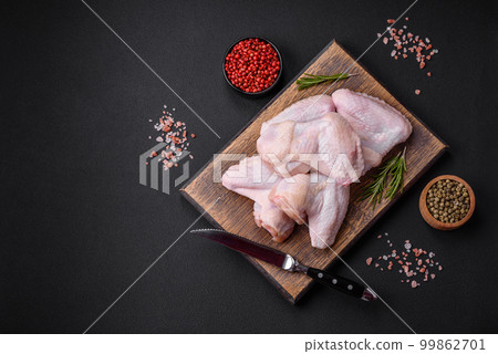 Raw chicken wings with salt, spices and herbs on a wooden cutting board Raw chicken wings with salt, spices and herbs on a wooden cutting board 99862701