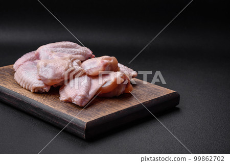 Raw chicken wings with salt, spices and herbs on a wooden cutting board 99862702