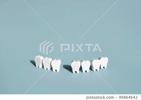 A model of teeth on a blue background with a missing front tooth . 99864642
