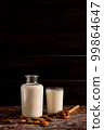 Almond milk in a bottle and a glass, on dark wooden background, with copy-space 99864647