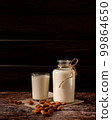 Almond milk in a bottle and a glass, on dark wooden background, with copy-space 99864650