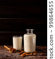 Almond milk in a bottle and a glass, on dark wooden background, with copy-space 99864655