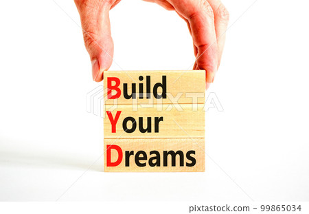 BYD build your dreams symbol. Concept words BYD build your dreams on wooden blocks on a beautiful white table white background. Businessman hand. Business and BYD build your dreams concept. Copy space 99865034