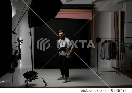 Professional handsome bearded male photographer with bunch of vintage photo cameras in photo studio. Professional handsome bearded male photographer with bunch of vintage photo cameras in photo studio. 99867581
