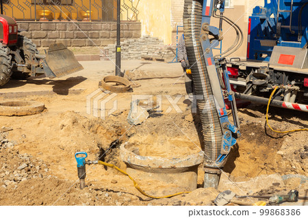 Workers use a suction excavator based on a truck to sample soil in a well for communications 99868386