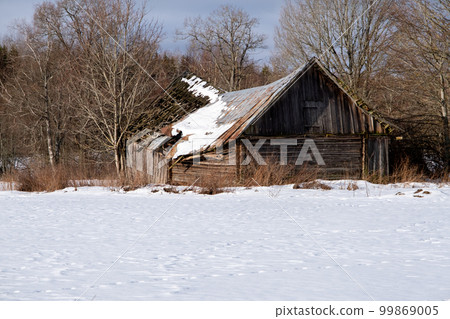 Old rural abandoned wooden collapsing house against cloudy sky in winter season 99869005