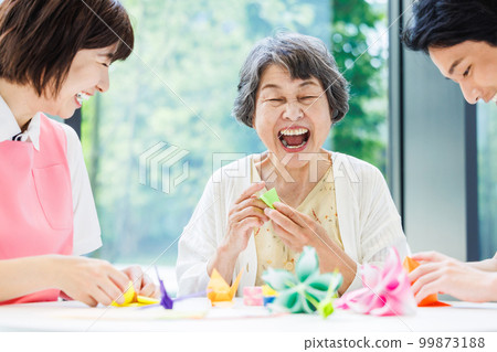 A senior woman folding origami and a caregiver Photography cooperation "LINK FOREST" 99873188