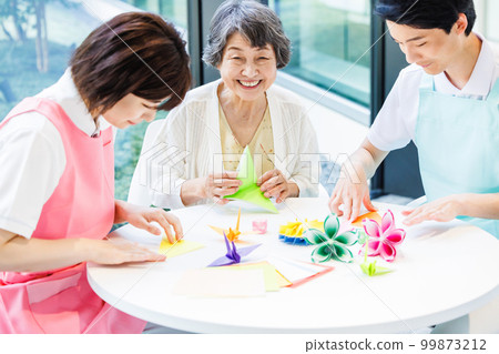 A senior woman folding origami and a caregiver Photography cooperation "LINK FOREST" A senior woman folding origami and a caregiver Photography cooperation "LINK FOREST" 99873212