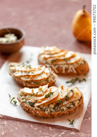 Roquefort french cheese and sliced peaches toasts on a square plate Roquefort french cheese and sliced peaches toasts on a square plate 99873702