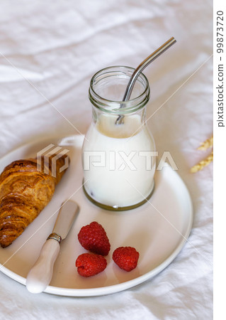 Coissant, milk and fresh berries, french breakfast on a bad 99873720