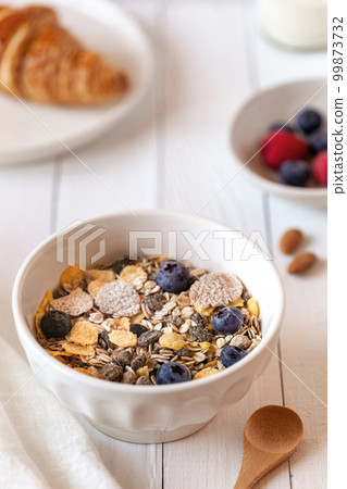 Breakfast bowl of oat flakes with berries, yoghurt and croissant Breakfast bowl of oat flakes with berries, yoghurt and croissant 99873732