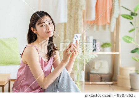 Young woman looking at her smartphone in the living room 99878623