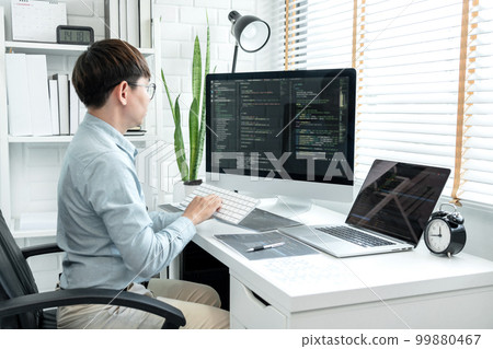 Male programmer is programming to develop program app and website of corporate while working to checking program code and debugging on multiple screen at modern software office 99880467