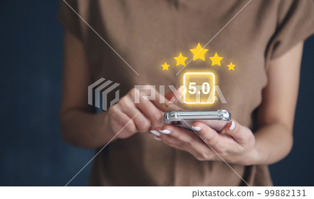 Hand using smartphone with popup five star icon for feedback review satisfaction service or business satisfaction survey. Hand using smartphone with popup five star icon for feedback review satisfaction service or business satisfaction survey. 99882131