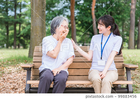 Elderly people talking in the park and a smiling nursing staff woman (talking/fun) 99883456