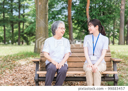 Elderly people talking in the park and a smiling nursing staff woman (talking partner, talking, fun) 99883457