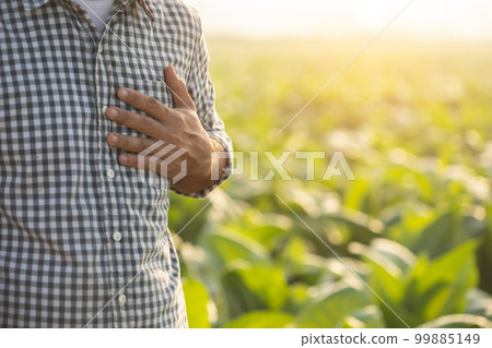 injuries or Illnesses, that can happen to farmers while working. Man is using his hand to cover over left chest because of hurt,  pain or feeling ill 99885149
