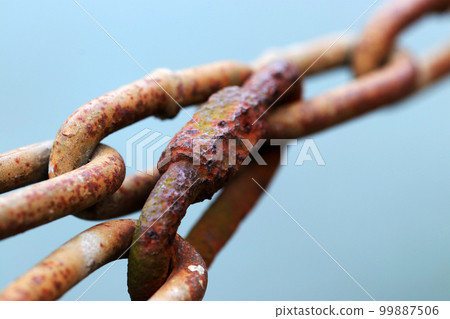 A macro close-up image of an old, rusty, rugged steel chain and lock against a blue sky. A macro close-up image of an old, rusty, rugged steel chain and lock against a blue sky. 99887506