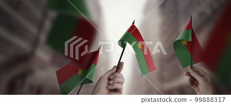 A group of people holding small flags of the Burkina Faso in their hands A group of people holding small flags of the Burkina Faso in their hands 99888317