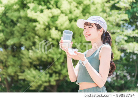Woman drinking protein while training in the park Woman drinking protein while training in the park 99888754