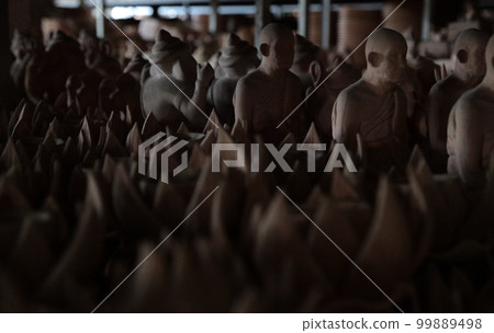 Thai Theravada Buddhism monks and many Buddhist altar fittings sleeping in the drying and unglazed storage of Chiang Mai Ceramics Studio, Thailand 99889498