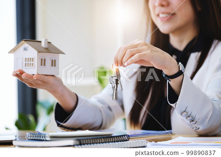 Accountant, businessman, real estate agent, Asian business woman handing house keys to customers along with house interest calculation documents for customers to sign Accountant, businessman, real estate agent, Asian business woman handing house keys to customers along with house interest calculation documents for customers to sign 99890837