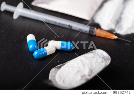 Drugs in tablets and powder, a syringe lies nearby 99892741