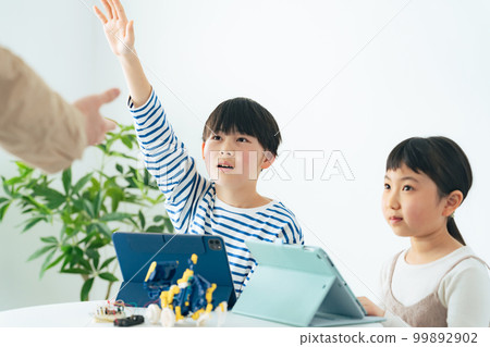 一個女孩和一個男孩在編程課上學習如何操作機器人 99892902