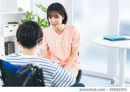 A female healthcare worker examining a boy in a wheelchair 99892905
