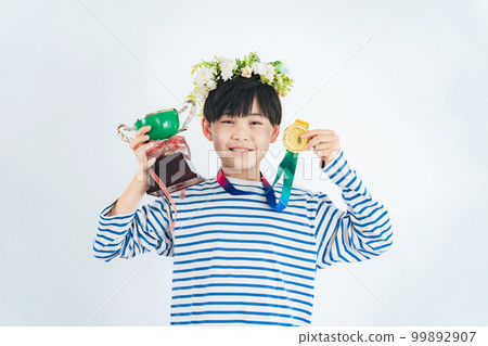 Boy showing the winning cup with gold medal 99892907