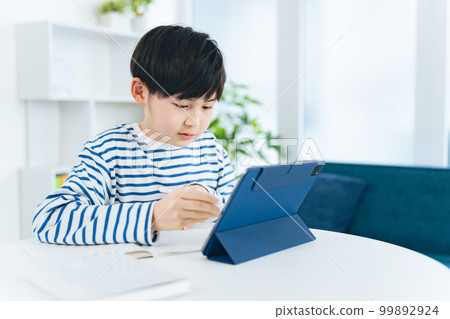 A boy studying while looking at a tablet 99892924