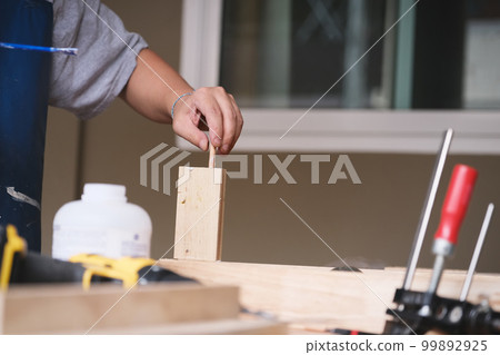 Woodworking operators are using glue to put together the wood parts to assemble and build a wooden table for their customers. Woodworking operators are using glue to put together the wood parts to assemble and build a wooden table for their customers. 99892925