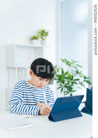 A boy studying while looking at a tablet 99892926