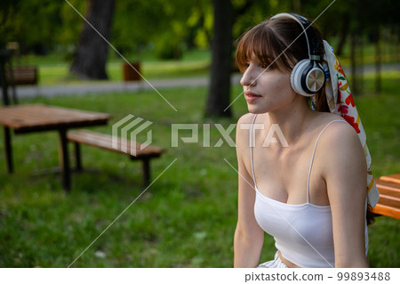 A young girl with fringe listens to music in the park. A young girl with fringe listens to music in the park. 99893488