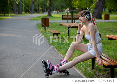 A girl relaxes while sitting on a park bench 99893491