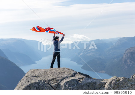 Woman with a waving flag of Norway on the background of nature 99895910