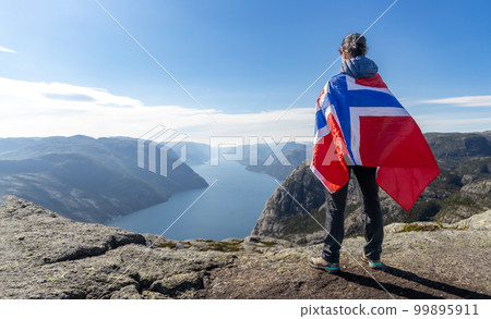 Woman with a waving flag of Norway on the background of nature 99895911