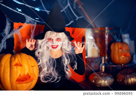 Little girls in witches carnival costume scaring and making faces on background decor Halloween Little girls in witches carnival costume scaring and making faces on background decor Halloween 99896095