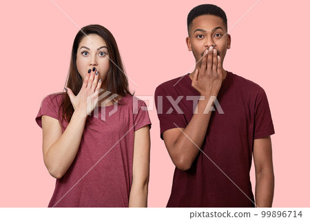 Waist up shot of surprised mixed race girlfriend and boyfriend being in stupor, cover mouth with palm, being shocked by terrific news, isolated over pink background. Diversity and reaction concept Waist up shot of surprised mixed race girlfriend and boyfriend being in stupor, cover mouth with palm, being shocked by terrific news, isolated over pink background. Diversity and reaction concept 99896714