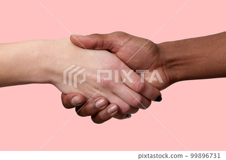 Horizontal shot of handshake between African American man and Caucasian woman pose over pink background, greet each other, demonstrate international relationship. Close up shot. Shaking hands 99896731