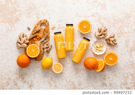 Smoothie. Healthy fresh raw detox citrus smoothie with orange, lemon, ginger and turmeric in a glass bottles on a table. Healthy diet vegan food full of antioxidants 99897252