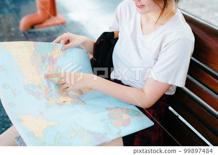 summer, relax, vacation, travel, portrait of a cute Asian girl looking at a map to plan a trip while waiting at the train station summer, relax, vacation, travel, portrait of a cute Asian girl looking at a map to plan a trip while waiting at the train station 99897484