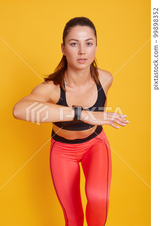 Woman runner posing isolated over yellow studio background, dynamic movement, fit lady working out in gym, wearing bra and leggins, strong and sporty female. Sport and healthy lifestyle concept. Woman runner posing isolated over yellow studio background, dynamic movement, fit lady working out in gym, wearing bra and leggins, strong and sporty female. Sport and healthy lifestyle concept. 99898352