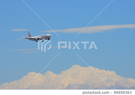 Passenger plane flying in the summer sky: Passenger plane approaching landing 99898363