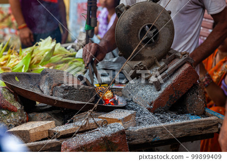 ndian man hands roasting corn, the indian street food at street market. 99899409