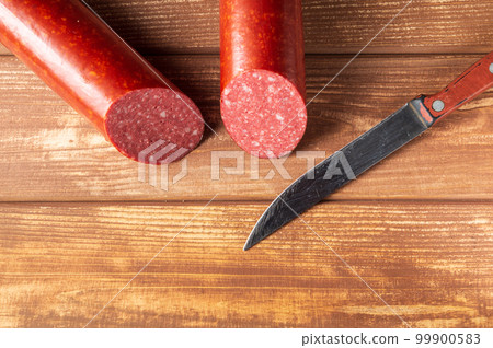 Sliced salami sausage and knife on cutting board. Food preparation idea Sliced salami sausage and knife on cutting board. Food preparation idea 99900583
