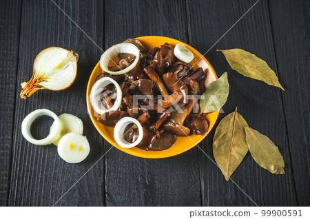 Armillaria mellea or honey fungus marinated in a yellow plate with spices and onions on a vintage table. Idea for a delicious snack for lunch. Top view Armillaria mellea or honey fungus marinated in a yellow plate with spices and onions on a vintage table. Idea for a delicious snack for lunch. Top view 99900591