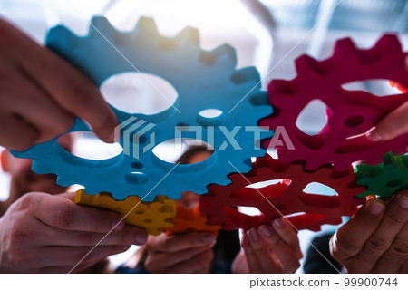 Teamwork of business people work together and combine pieces of gears 99900744