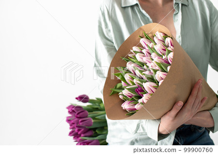 A large bouquet of tulips of different colors in the hands of a woman A large bouquet of tulips of different colors in the hands of a woman 99900760